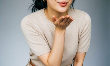 A medium shot photo of a woman looking directly into the camera. She leans forward